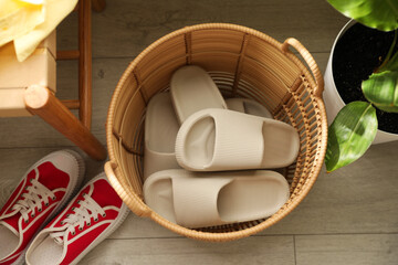 Basket with slippers for guests and sneakers in entryway at home, above view