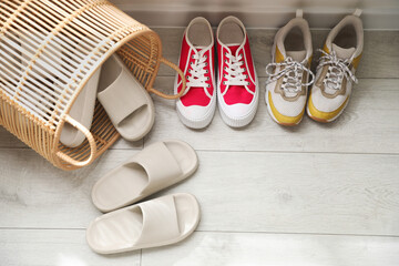 Basket with slippers for guests and sneakers in entryway at home, above view