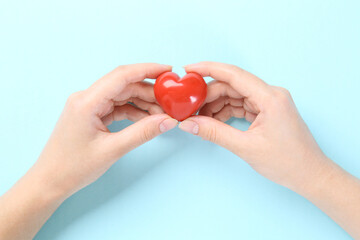 Woman with red heart on light blue background, closeup