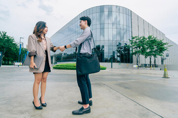 Two business man and woman shake hands outside a modern office building and successful business...