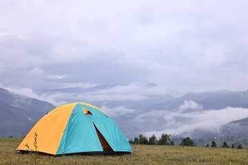 Tent on green grass in mountains, space for text