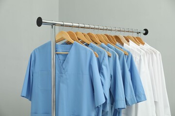 Obraz premium Different medical workers' uniforms on clothing rack against grey background