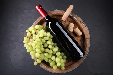 Corkscrew, bottle of wine, grapes, corks and wooden barrel on grey table, top view