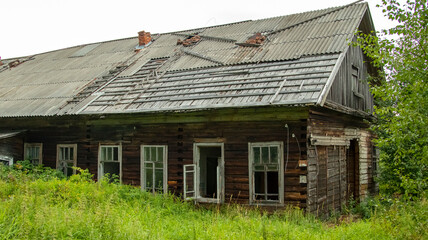 broken windows of an abandoned village house overgrown with grass