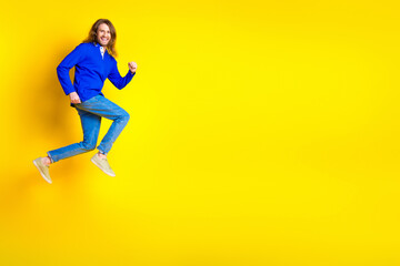 Photo of attractive positive cheerful man wear trendy blue clothes run empty space isolated on yellow color background