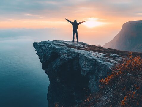 Conquering the Summit: A lone figure stands triumphant on a clifftop, arms outstretched, silhouetted against a breathtaking sunset over the ocean. This image evokes feelings of freedom.