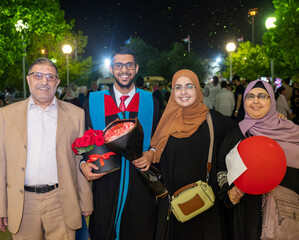 family moment celebrating brother graduation during night having portrait together
