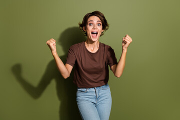 Fototapeta premium Portrait of overjoyed crazy girl with short hairdo wear oversize t-shirt scream yeah win betting isolated on green color background