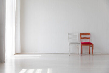 Two old vintage chairs in the interior of a white room near the wall