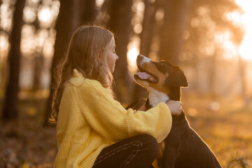 Obraz premium little teenage girl walks with her dog in the autumn in the forest
