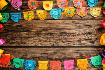 Celebrate with Colorful Fiesta Decorations: Vibrant Papel Picado Banners on Rustic Wood Background