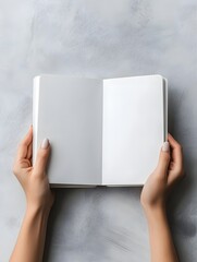 Female holding blank notebook on light gray surface from above, ideal for design mockups