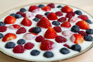 In a plate with freshly whipped cream juicy berries strawberries raspberries and blueberries