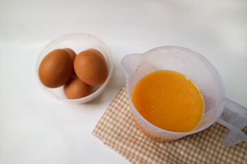 food preparation photography concept. whisking egg on white plastic measuring cup. Isolated background in white.
