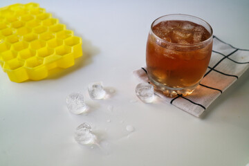 Ice tea with ice cubes mold on the side, isolated on white background. Iced tea is a refreshing...