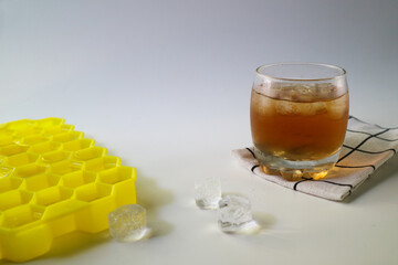 Ice tea with ice cubes mold on the side, isolated on white background. Iced tea is a refreshing...