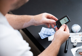 Men check their sugar levels using a lancet pen and glucometer