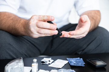 Men check their sugar levels using a lancet pen and glucometer