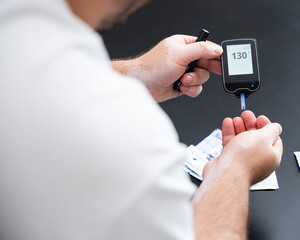 Men check their sugar levels using a lancet pen and glucometer