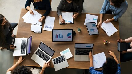 Businesspeople in a meeting discussing data on laptops and tablets.