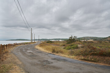 Old road with no one on it, with a curve at the end and a stormy sky with no one on it