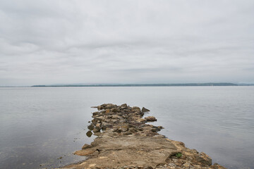 rocks in the middle of the sea that go into the water with the horizon in the background with a sky with storm clouds
