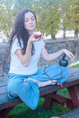 Woman Eating an Apple While Holding a Kettlebell Outdoors