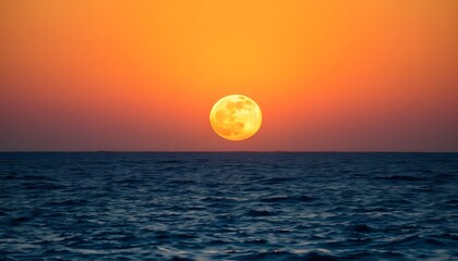 A full moon rising over a dark ocean at sunset, with an orange and red sky in the background
