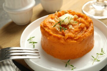 Plate with tasty mashed sweet potato, butter, thyme and walnuts served on table, closeup