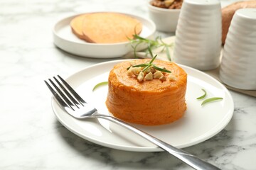Plate with tasty mashed sweet potato, rosemary and walnuts on white marble table, closeup