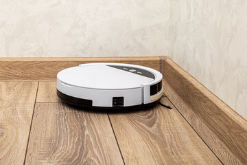 Robot vacuum cleaner is vacuuming in the corner of the room. Hard-to-reach place for cleaning