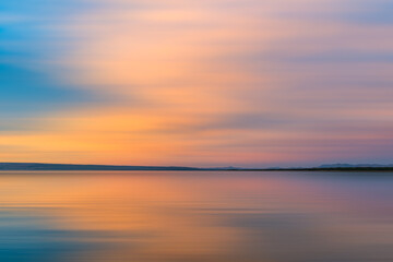 Obraz premium Sunset light across a calm lake