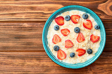 Homemade breakfast . Oatmeal with milk and berries . Top view