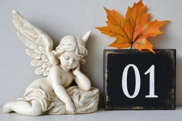 A cute angel figurine sits by an autumn leaf and a calendar which marks November 1.