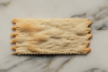 single artisan cracker on white marble