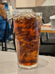 Iced cola soft drink in glass on table in restaurant. Beverage menu