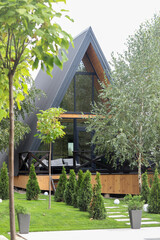 A-frame House. Modern new frame country house standing in a mixed forest in front of the camera against the backdrop of trees.