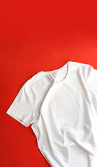 Blank folded white t-shirt, on red white background. Close-up of a simple white t-shirt mockup
