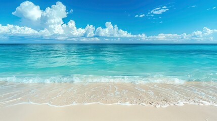Tranquil seascape with white clouds in a blue sky above a sandy beach with calm waves.