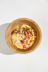 Healthy Mango Smoothie Bowl with Wild Rice, Coconut, and Raspberries in Wooden Bowl