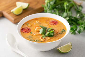 Tom yum soup with shrimps in white bowl on light background with copy space. Popular traditional asian cuisine