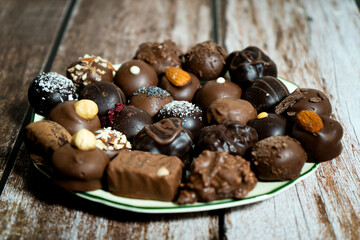 Assortment of fine chocolate bonbons on a plate on a wooden table.