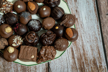 Assortment of fine chocolate bonbons on a plate on a wooden table.