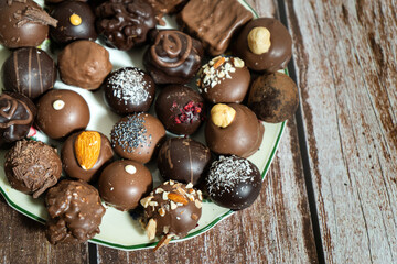 Assortment of fine chocolate bonbons on a plate on a wooden table.
