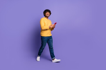 Photo of cheerful cool latin man wear trendy yellow clothes hold modern gadget isolated on purple color background