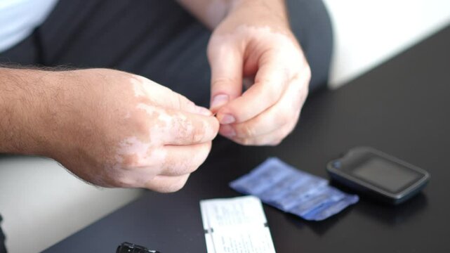 Men check their sugar levels using a lancet pen and glucometer