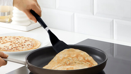 Closeup of a person flipping pancakes in a frying pan.