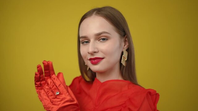 A stylish woman, adorned in red gloves and exquisite jewelry, radiates elegance against a vibrant backdrop