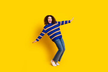 Full size photo of funky good mood woman dressed striped sweater dancing hold balance on tiptoes isolated on yellow color background