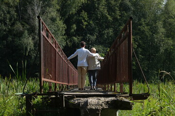 Couple, mother and adult son on the narrow bridge. Photo was taken 15 August 2024 year.